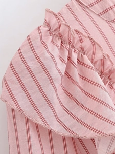 Detailed view of pink striped fabric with ruffled layers and delicate stitching details