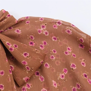 Detail of brown chiffon fabric with pink floral print and elegant bow tie design