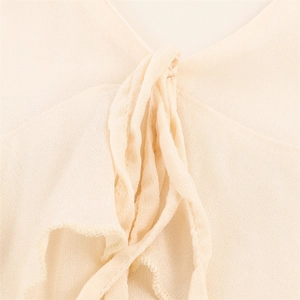 Close-up of ruffled neckline and adjustable ties on a cream-colored chiffon blouse