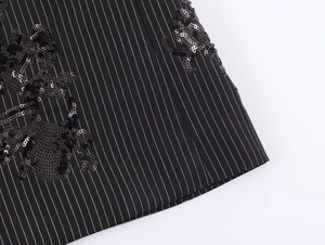 Detail of black pinstripe suit fabric featuring intricate embroidery and shimmering sequins