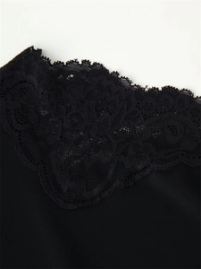 Détail de la robe noire montrant la dentelle florale délicate et les finitions