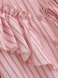 Detail of pink striped shirt showing tiered ruffles and matching four-hole buttons