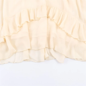 Detail view of cream chiffon dress showing multi-layered ruffle design and soft texture