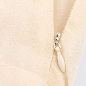 Close-up of the concealed zipper on the light beige chiffon fabric of the dress