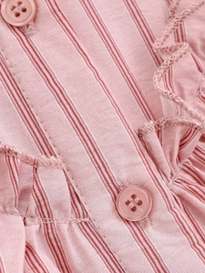 Macro detail of pink striped fabric featuring layered ruffles and matching resin buttons