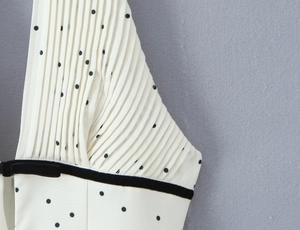 Détail du tissu blanc à pois avec plis élégants et bordure en ruban de velours noir
