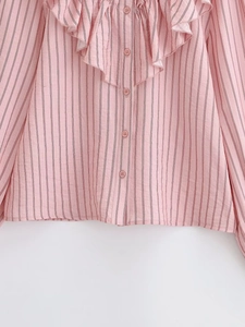 Detail view of ruffled layers and red vertical stripes on a pink standing collar shirt