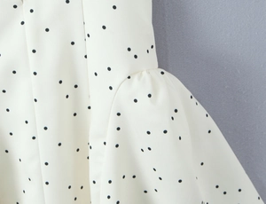 Détail de pois noirs sur tissu crème avec ourlet à volants et coutures de précision