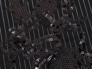 Close-up of black sequin embroidery on vertical striped fabric for women suit
