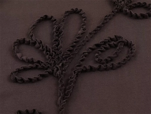 Detail of brown fabric featuring ribbon embroidery and ruffled floral texture design