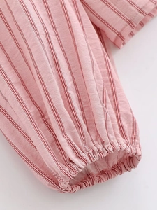 Detail of pink striped sleeve with elastic ruffled cuffs and textured cotton fabric