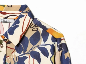 Détail du col d'une chemise en satin à imprimé feuilles avec des boutons orange élégants