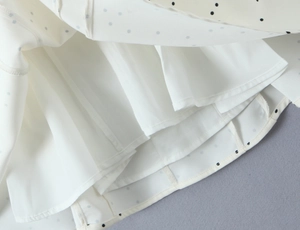 Détail d'une robe blanche à pois montrant la mousseline légère et la doublure