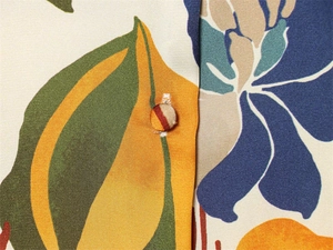 Vue macro d'une chemise satinée aux imprimés floraux rétro avec un bouton recouvert assorti