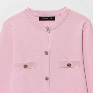Dettaglio del cardigan in maglia rosa con bottoni dorati e scollatura a girocollo