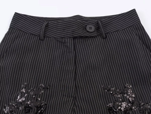 Detailed macro view of black striped suit pants with shimmering sequin embroidery details