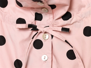 Close-up of pink polka dot fabric with mother-of-pearl buttons and tie detail