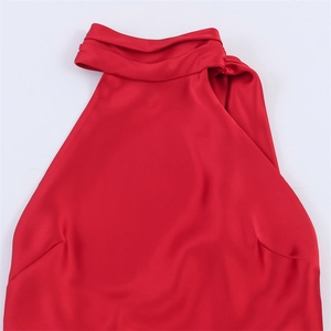 Détail d'une robe rouge satinée avec encolure licou, plis élégants et texture soyeuse