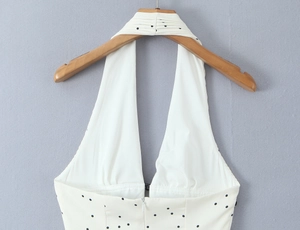 Détail d'une robe licou à pois avec décolleté en V profond et bretelles plissées au cou