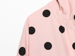 Macro shot of pink fabric showing neckline detail and black polka dot pattern