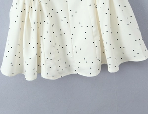 Détail d'une robe d'été blanc crème à pois noirs avec un tissu plissé et fluide élégant