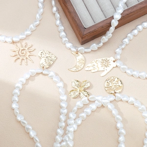Detail of bohemian heart pearl necklaces with various gold sun, moon, and heart charms