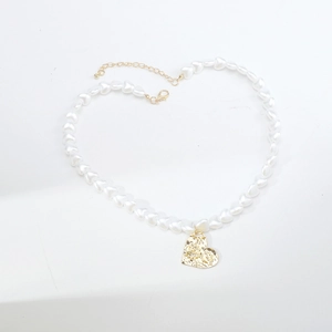 Detailed shot of white heart-shaped pearl necklace with gold textured heart pendant