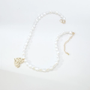 Detailed view of elegant white heart pearl necklace with a textured gold heart pendant.