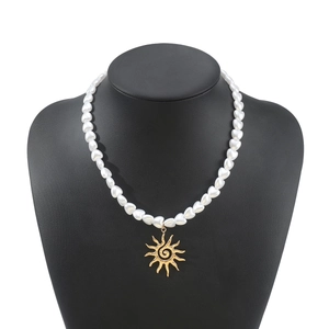 Close-up of heart-shaped pearl necklace featuring a golden sun pendant on a mannequin