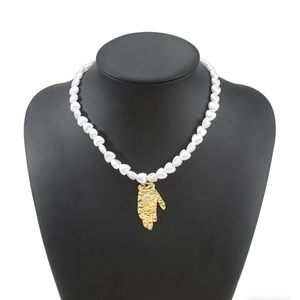 Vintage pearl necklace with golden Hamsa hand pendant displayed on black mannequin