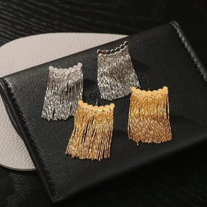 Modern arc-shaped tassel earrings in gold and silver finish displayed on leather