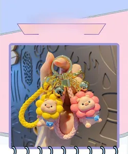 Close-up of pink and yellow cartoon pig sunflower keychains with woven lanyards