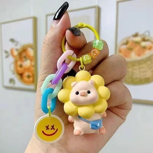 Close-up of pink pig keychain with sunflower, blue bag detail and colorful chain