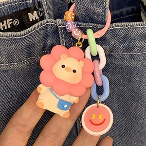 Detailed close-up of a cute piggy keychain with colorful chains and a sunflower on denim
