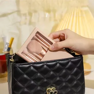 Pink makeup brush set inside a compact case with mirror being put into a black quilted bag
