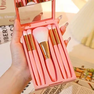 Pink portable 5-piece makeup brush set with mirrored case held in a warm lifestyle setting