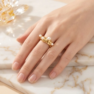 Bague vintage en acier doré texturé ornée de cinq perles blanches portée au doigt