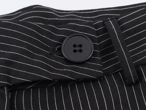 Detail view of black pinstripe suit trousers featuring a round button and stitching