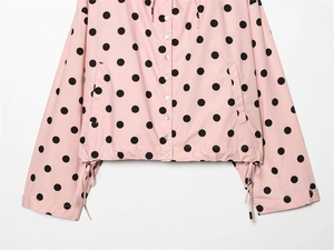 Detail of pink polka dot jacket with white buttons and adjustable drawstring hem