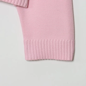 Dettaglio del cardigan in maglia rosa con trama fine e bordi a coste rifiniti