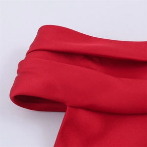 Gros plan sur l'épaule dénudée en satin rouge avec détails de couches et texture soyeuse