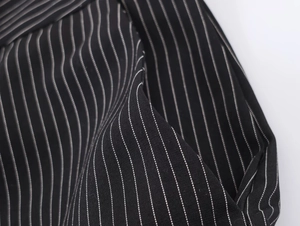 Close-up of black pinstripe fabric showing twill texture and quality sewing details