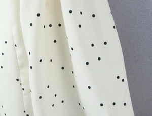 Vue macro détaillée du tissu blanc à pois noirs présentant une texture légère et fluide