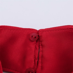 Gros plan sur une robe en satin rouge avec bouton rond à deux trous et coutures précises