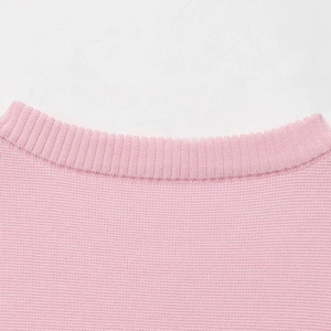 Dettaglio macro del maglione in maglia rosa tenue con scollo rotondo a costine