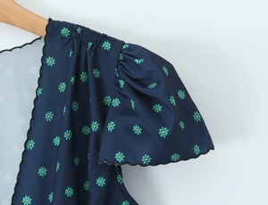 Close-up of deep blue floral dress featuring puff sleeves and scallop edge detail