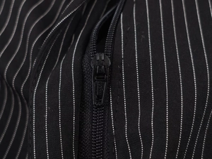 Macro detail of black pinstripe fabric with a branded CHEST embossed zipper head