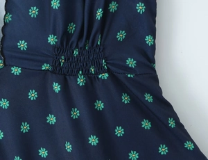 Detailed view of elastic smocking craft on dark blue floral print summer dress fabric