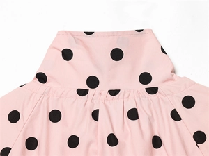 Detail of pink polka dot blouse with high neckline and gathered pleats on soft fabric