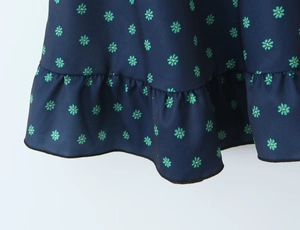 Detailed macro shot of navy floral print fabric with ruffled hem and fine stitching